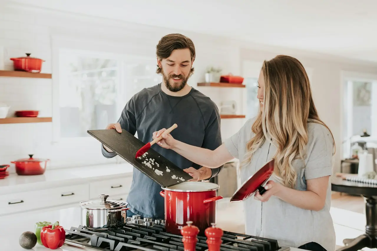 Two people cooking in a kitchen with open shelving